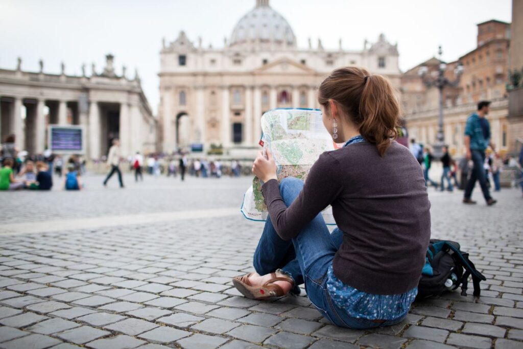 Female traveller sitting on the ground looking at a map - Backpacker First World Problems