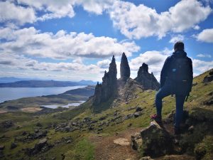 Woman hiking on the Old Man of Storr on the Isle of Skye in front of an epic view of Scottish Mountains