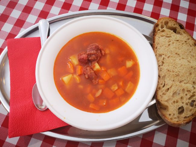 Bowl of Goulash soup with a slice of bread and red napkin