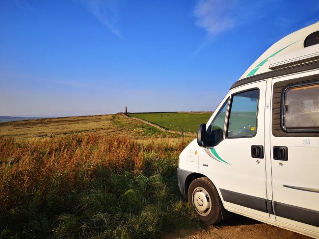 Occasionally You Find a Great Parking Spot - Mabel the Motorhome in a Scenic Car Parking looking out over green fields with a stone tower in the distance