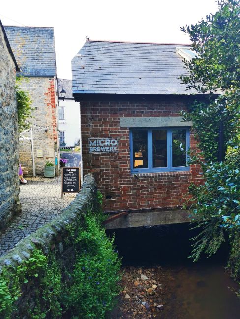 The Brewery at the Old Mill, an image of the stone building from the outside over a small stream that is the River Lim- THe Best Things to do in Lyme Regis Dorset