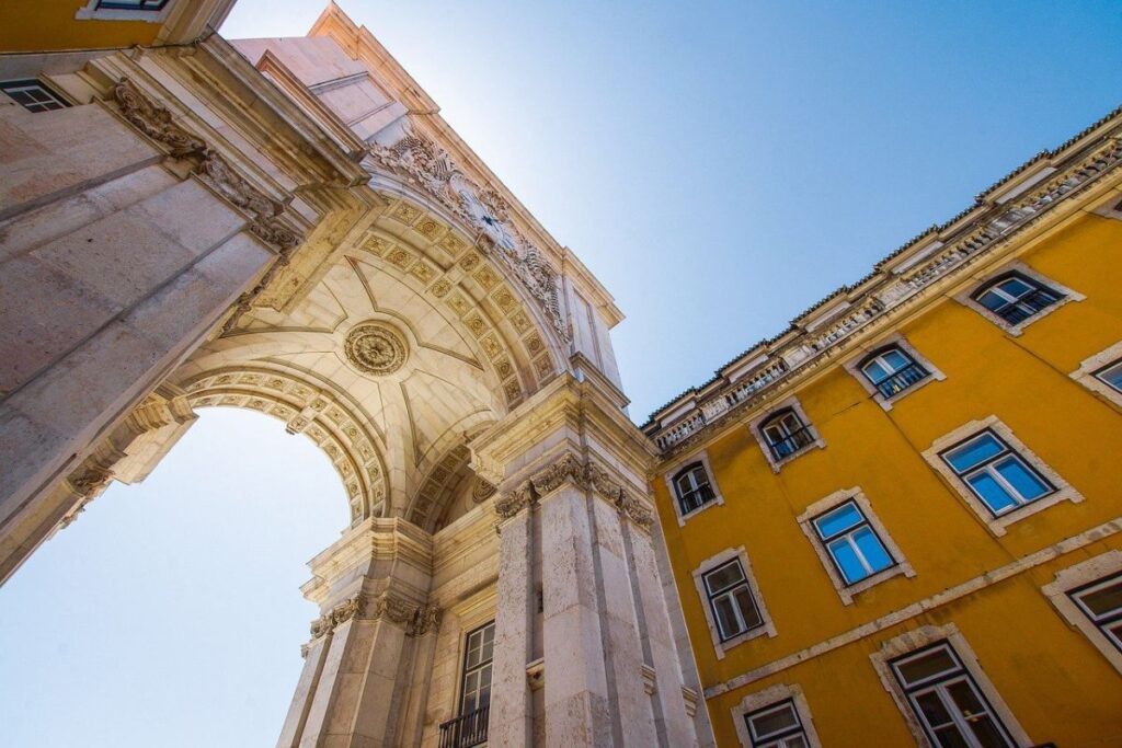 Archway in Lisbon from below, with the sun shining over the arch - Why Visit Lisbon in Winter - The Best Things to do in Lisbon Portugal