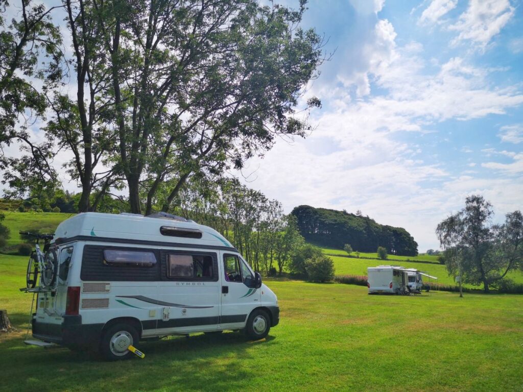 Mabel the Motorhome parked in a field under a tree on a sunny day