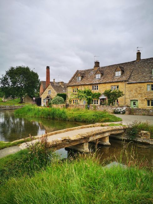 Cotswold cottages and the Old Mill across the river in Picturesque Lower Slaughter