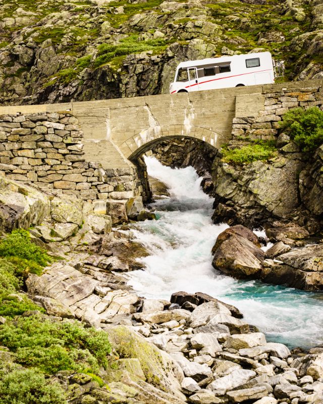 A Stone bridge over a river with a campervan driving over the bridge - Where Will You Go on Your Van Road Trip