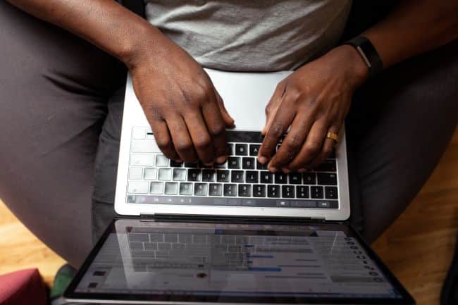 overhead view of a Man with a laptop on his lap with his hands on the laptop keys
