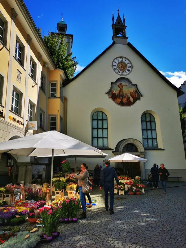 Flower stalls with a chapel behind them in Marktplatz in Feldkirch