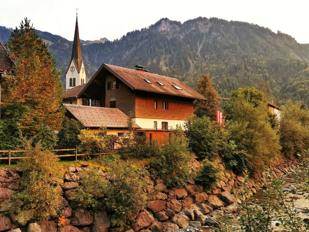 Rustic building and church in autumn in the village of Mellau - Things to do in Vorarlberg Austria