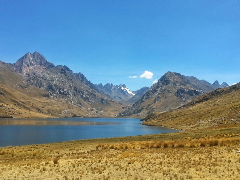 A Blue lake with mountains in the background - Laguna Querococha in Peru - Peru Backpackers Guide