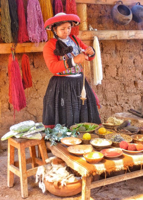 Traditional Weaving in Peru - woman in traditional dress with a table full of coloured dyes for making yarn