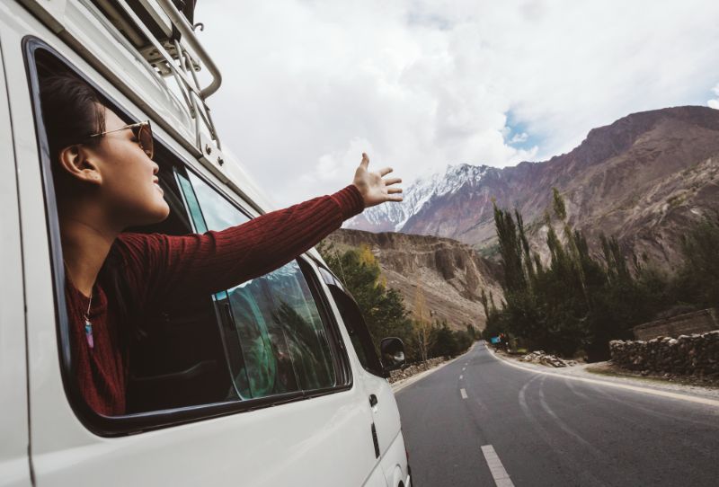 Woman with arm out of a car window enjoying travel