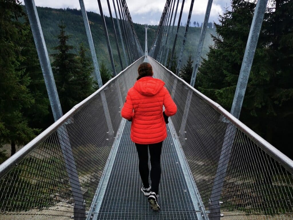 Me wearing a dark coral coloured Drax Hooded Down Jacket on the longest suspension bridge in the world - TOG24 Drax Hooded Down Jacket - TOG24 Review
