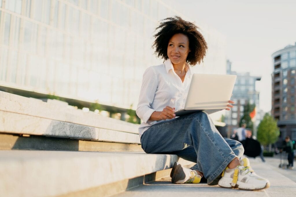Woman with a laptop sitting outside - Digital Nomad Essentials