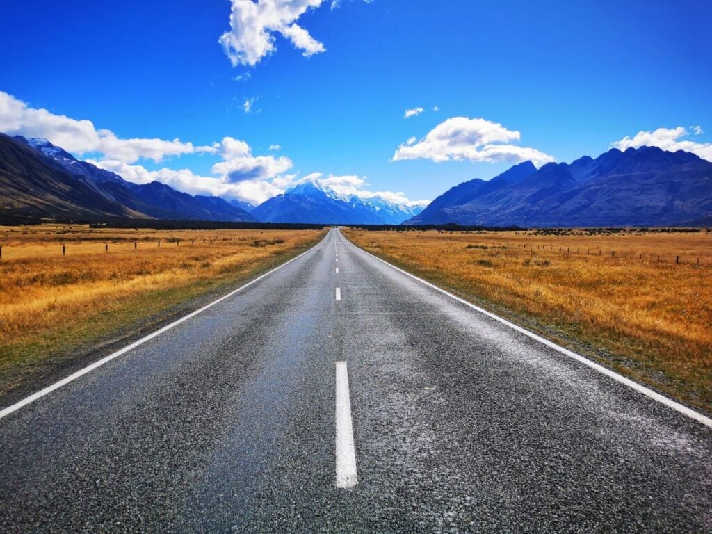 Heading Out on a Road Trip - Scenic Road with Mountains in the Background - Road Trip Essentials Packing List