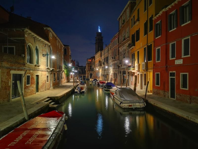Not Exploring Venice at Night is a Huge Tourist Mistake - A Canal in Venice at night with boats on the edge of the canal