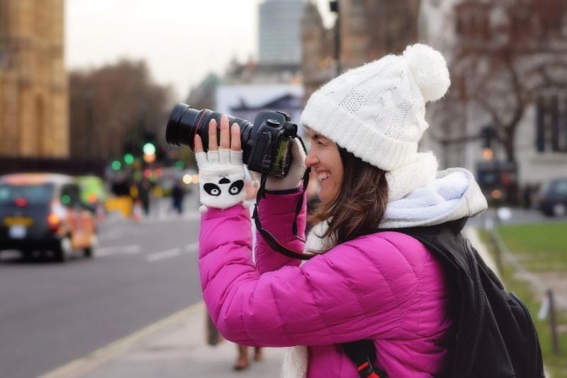A Woman Taking a photograph in London Wearing Warm Winter Clothes